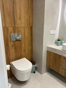 a bathroom with a white toilet and a wooden wall at Apartament N32 in Garwolin