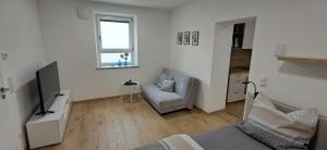 a white living room with a couch and a television at kreuzwirt bayern in Essenbach