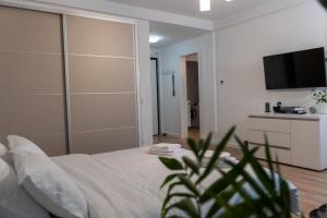 a bedroom with a large white bed with a flat screen tv at Vanguard Suite De Lux in Craiova