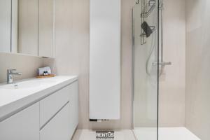 een witte badkamer met douche en wastafel bij Newport 3 - luxury apartment with side sea view in Nieuwpoort