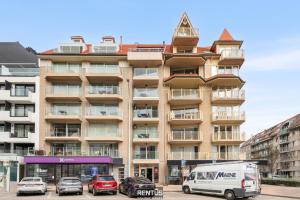 een groot gebouw met auto's ervoor geparkeerd bij Newport 3 - luxury apartment with side sea view in Nieuwpoort