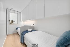 een witte slaapkamer met twee bedden en een raam bij Newport 3 - luxury apartment with side sea view in Nieuwpoort