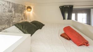 una cama blanca con dos almohadas y una manta naranja en BonAppart 13 - Charme Napoléonien & Confort, en Troyes
