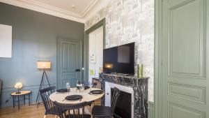 Una sala de estar con una mesa y una chimenea. en BonAppart 13 - Charme Napoléonien & Confort, en Troyes