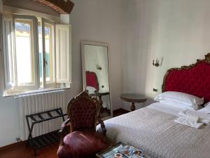 a bedroom with a bed and a chair and a window at La Casa di Dante Fiesole in Trespiano