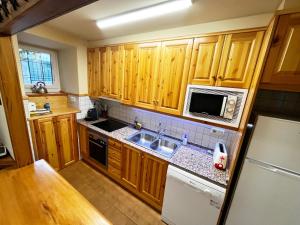 a kitchen with wooden cabinets and a sink and a microwave at SNÖ Casa Pucurull in Salardú