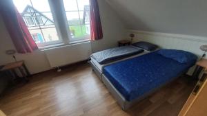 1 Schlafzimmer mit einem Bett mit blauer Bettwäsche und 2 Fenstern in der Unterkunft Haus am Golfplatz Cochem Mosel in Ediger-Eller
