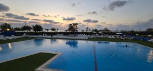 a large swimming pool with white chairs and a sunset at GoldSea - Boutique Seafront Studio in Nahariyya