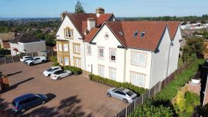 a large white house with cars parked in a parking lot at Highfields House Spinny Hill Northampton in Spinney Hill
