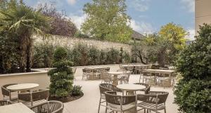 a patio with tables and chairs and a wall at Best Western Plus Hotel Saint-Roch Orleans in Orléans