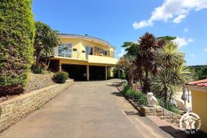 a large yellow house with palm trees and a driveway at La rose des vents in La Chèze