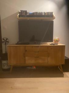 a large television on top of a wooden entertainment center at Chez Nico in Frans