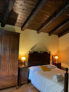 a bedroom with a large bed with wooden ceilings at Cascina Bolichin appartamento Mentha in Rodello