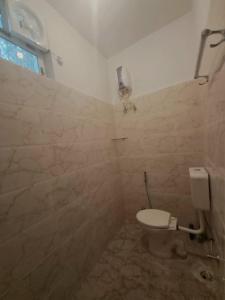 a bathroom with a toilet and a tiled wall at The Happy Homestay in Nāmkom