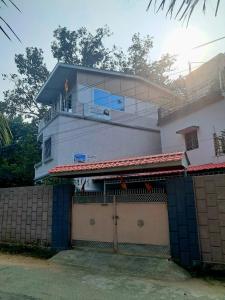 a white house with a gate and a fence at The Happy Homestay in Nāmkom +6 photos