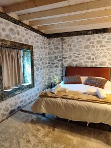 a bedroom with a large bed in a stone wall at Tommy's Guest House in Konitsa