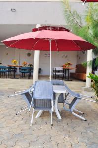 a table and two chairs under a red umbrella at Shamo Inn And Lounge Mukono in Mukono