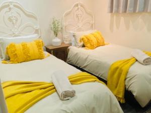een kamer met 2 bedden met gele en witte lakens bij Wild Olive at 51 in Windhoek