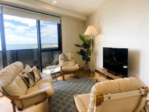 a living room with two chairs and a flat screen tv at MERCER APARMENTS 2 Bedroom Apartment with Bay Views on the Geelong Waterfront - 609 in Geelong