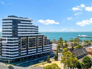 an office building with the ocean in the background at MERCER APARMENTS 2 Bedroom Apartment with Bay Views on the Geelong Waterfront - 609 in Geelong