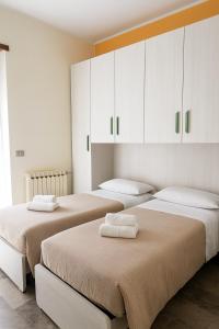 - 2 lits dans une chambre avec des armoires blanches dans l'établissement Corno Grande - spacious apartment - 2 baths - Wi Fi- city center - free parking, à LʼAquila