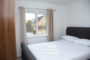 een slaapkamer met een wit bed en een raam bij Peterborough Haven: 3BD Family Home Retreat in Peterborough