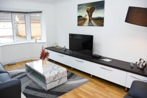 een woonkamer met een tv aan een witte muur bij Peterborough Haven: 3BD Family Home Retreat in Peterborough