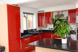een keuken met rode kasten en een potplant bij Peterborough Haven: 3BD Family Home Retreat in Peterborough