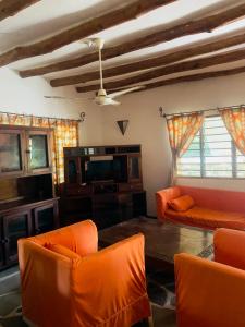 sala de estar con muebles de color naranja y TV en Casuarina road 2 bedroom villa, en Malindi