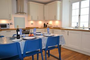 a kitchen with a table with blue chairs and white cabinets at Manor House Apartment 2 in Shaldon