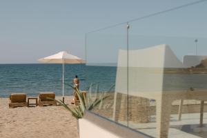 a man standing on the beach under an umbrella at Costel BeachFront Residence, BBQ & Private Sunbeds, By ThinkVilla in Fodele +46 photos
