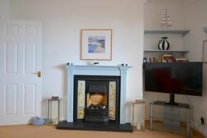 a living room with a fireplace and a tv at Manor House Apartment 2 in Shaldon