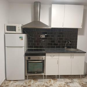 a kitchen with white cabinets and a stove and a refrigerator at Casa Damais in Seville