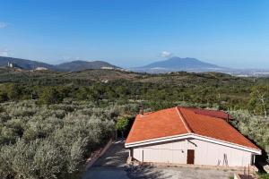 a white building with an orange roof with mountains in the background at Villa Aurora&Giulia in Avella