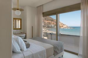 a bedroom with a bed and a view of the ocean at Costel BeachFront Residence, BBQ & Private Sunbeds, By ThinkVilla in Fodele