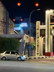 a car driving down a street in front of a hotel at New Caspian Hotel in Ipoh