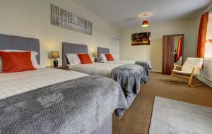 a hotel room with two beds and a chair at 5 bedrooms, sleeps up to 16, secure parking space & comfort in Skegby