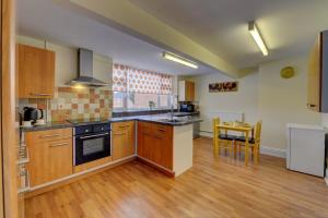 a kitchen with wooden cabinets and a stove top oven at 5 bedrooms, sleeps up to 16, secure parking space & comfort in Skegby +49 photos