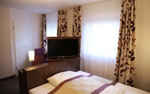 a bedroom with a bed and a flat screen tv at Hotel Rothkamp in Frechen
