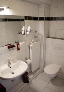 a white bathroom with a toilet and a sink at Hotel Rothkamp in Frechen