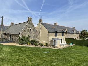 una gran casa de piedra con césped delante en Des puits, en Locoal-Mendon