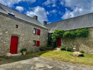 ein altes Steingebäude mit roten Türen und einem Hof in der Unterkunft Des puits in Locoal-Mendon