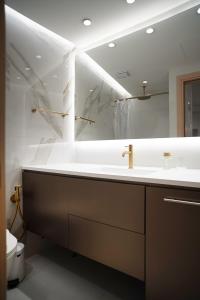 a bathroom with a sink and a large mirror at Koukaki Urban Suites in Athens