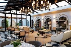 una sala de estar con mesas y sillas y un vestíbulo en Hospes Palacio de Arenales & Spa, en Cáceres