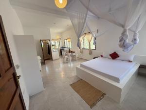 a bedroom with a white bed and a dining room at watamu New Arcade Comfort Suite in Watamu