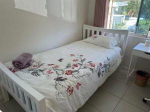 een wit bed met een witte sprei met bloemen erop bij UQ single bedroom with pool Q2 in Brisbane
