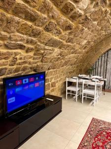 sala de estar con TV y pared de piedra. en Bab El Mina guest house Byblos, en Biblos