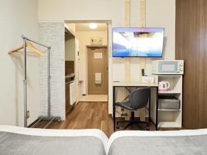 a room with a desk with a computer and a tv at Kurarisu Hakata クラリス博多 in Fukuoka