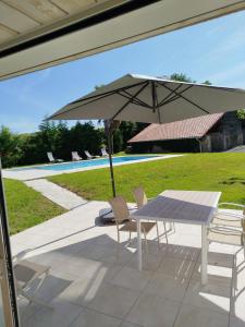 een tafel en stoelen met een parasol op een terras bij École des fans in Narrosse +12 foto's