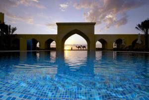 una piscina con puesta de sol en el fondo en Tilal Liwa Desert Retreat, en Medina Zayed